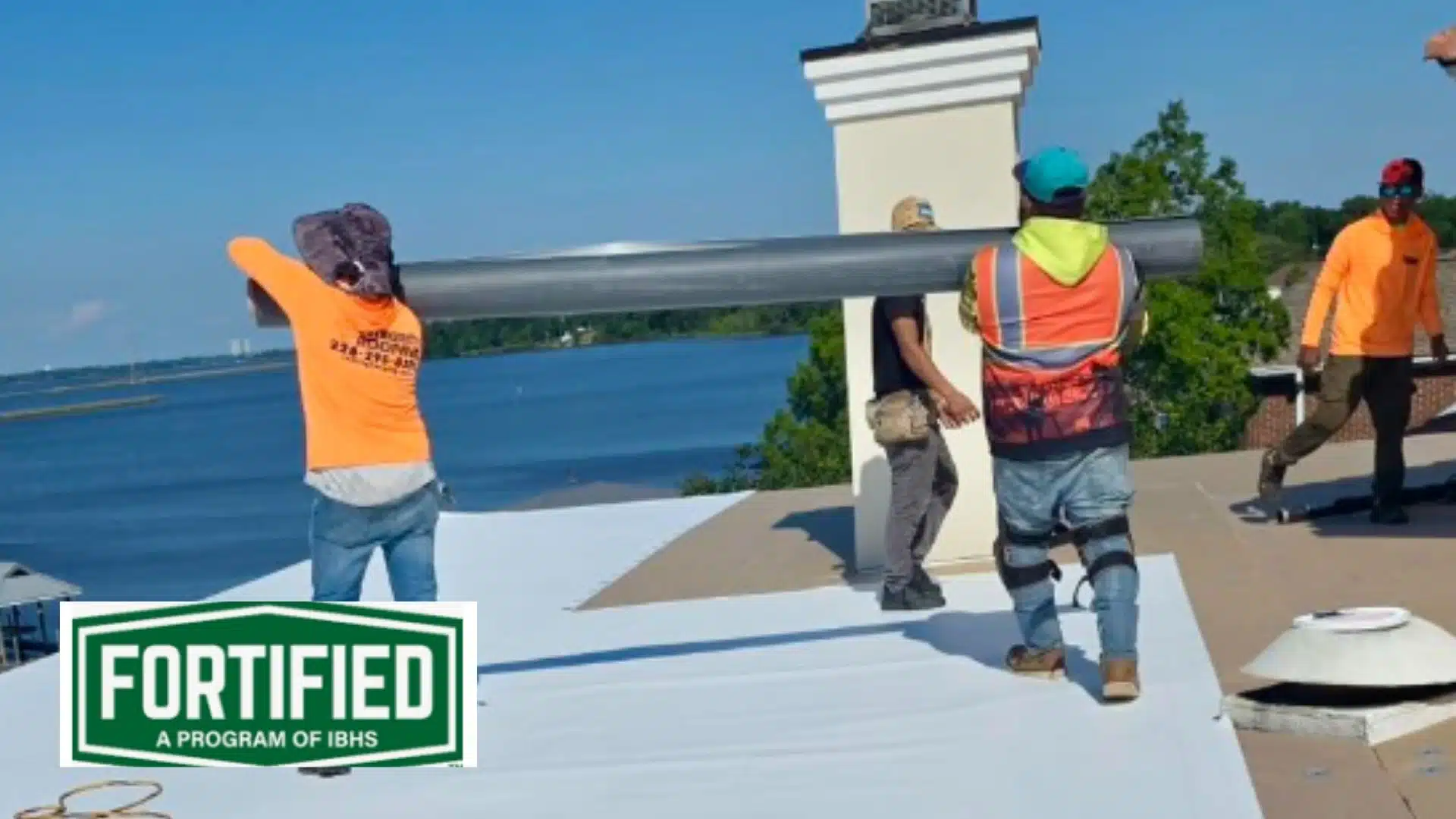 Integrity Roofing crew installing a Fortified commercial roof system in Gulfport MS, with FORTIFIED IBHS logo visible near the Mississippi coastline.