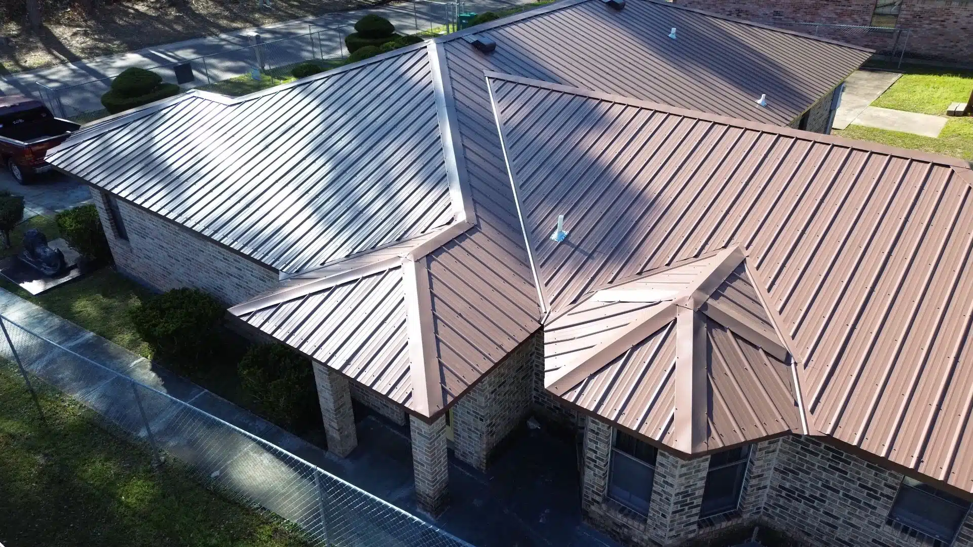 A brown metal FORTIFIED roof installed on a brick home by a top-rated MS Gulf Coast roofing contractor, designed to withstand high winds and hurricane conditions.