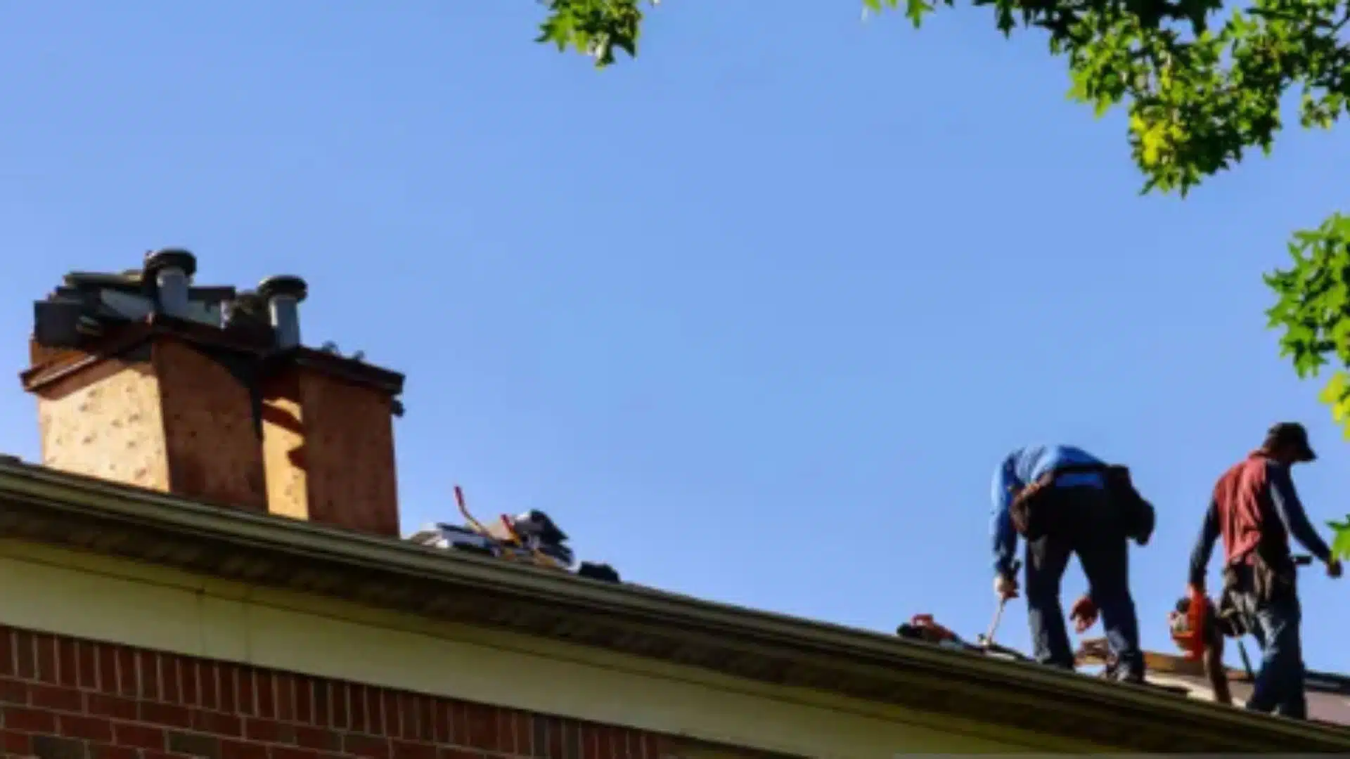 Licensed roofers conducting a hurricane-readiness roof inspection on a residential home in Gulfport, MS under a clear blue sky.