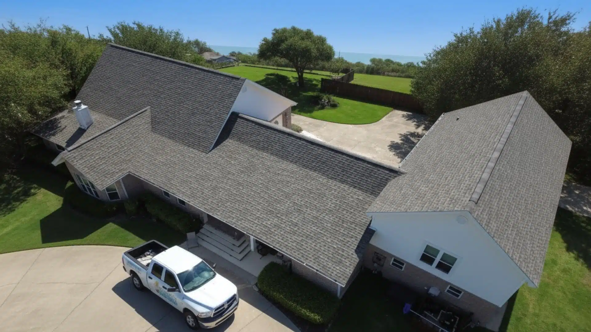 Integrity Roofing truck in front of a Gulfport MS home with a newly installed asphalt shingle roof after a storm, showing a safe and protected property under golden-hour light.