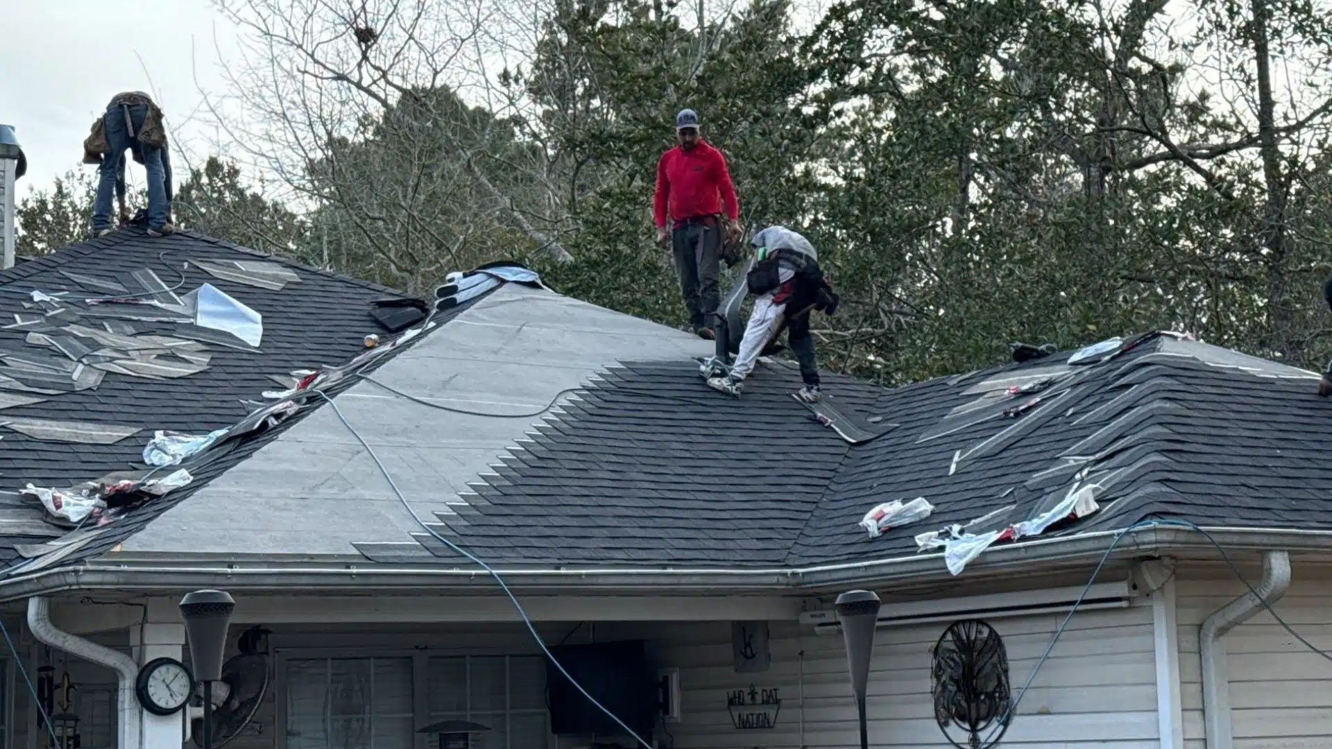 Roof replacement in progress on a home along the MS Gulf Coast with roofing crew installing new shingles