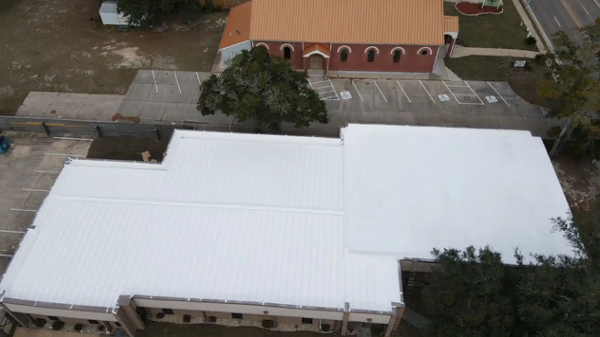 Aerial view of a white reflective cool roof installation on a commercial building in MS Gulf Coast